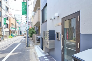 Una vista di strada con un edificio dotato di ingresso con cancello, una telecamera di sicurezza e un segnale che indica un'area di parcheggio.