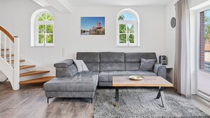 A modern living room with a grey sectional sofa, a wooden coffee table, and a staircase. - To the Anchorage - To the Anchorage: Vacation near Greetsiel with a large terrace (Krummhörn)