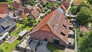 A residential area with multiple houses, a central building with a sloped roof, and a paved driveway. - To the Anchorage - To the Anchorage: Vacation near Greetsiel with a large terrace (Krummhörn)
