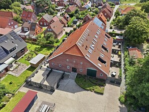 Ein Wohngebiet mit mehreren Häusern, einem zentralen Gebäude mit Satteldach und einem gepflasterten Einfahrt.