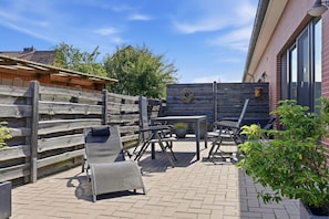Une terrasse extérieure avec une clôture en bois, une table et des chaises.