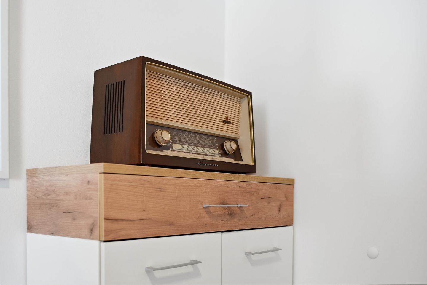 A vintage radio on a wooden cabinet with drawers.