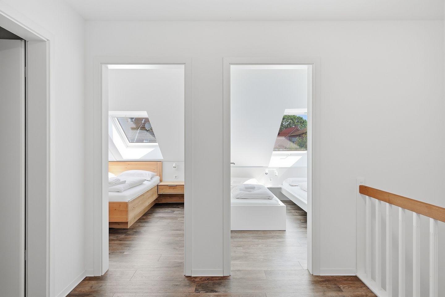 Un dormitorio moderno con tragaluz, una cama de madera y un armario blanco.
