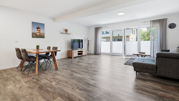 A spacious living area with a dining table, sofa, and a TV. - To the Little Lighthouse - To the Little Lighthouse: A Vacation in Idyllic Pilsum (Krummhörn)