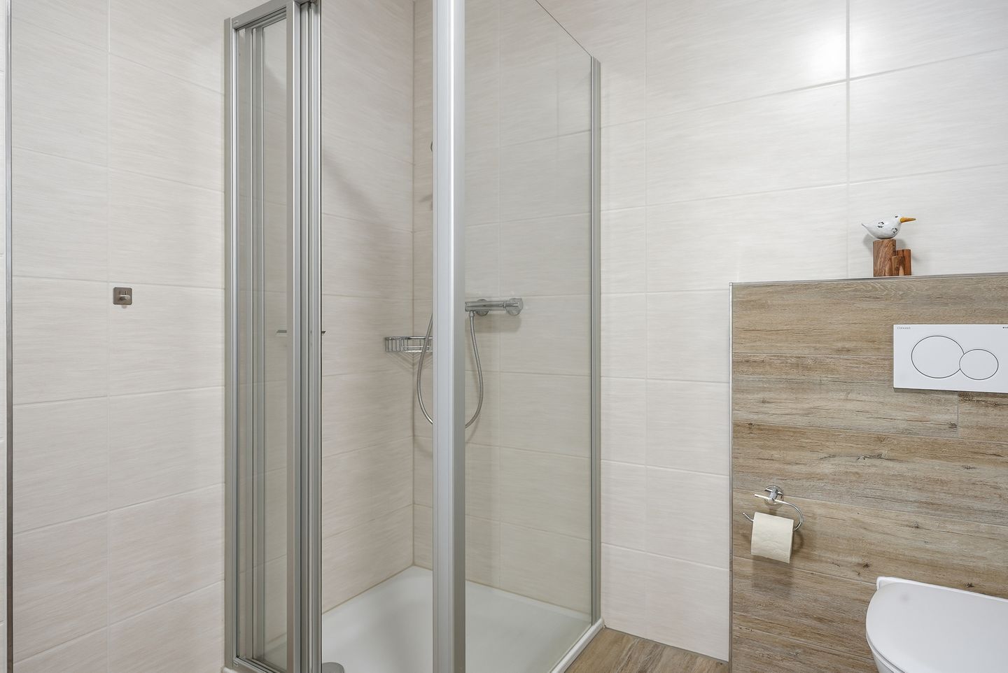 A modern bathroom with a glass shower enclosure, a wooden vanity, and a toilet.