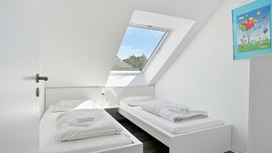 A modern bedroom with a skylight, two beds, and a view of the outdoors. - To the Little Lighthouse - To the Little Lighthouse: A Vacation in Idyllic Pilsum (Krummhörn)