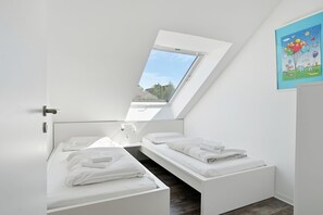 Ein modernes Schlafzimmer mit Dachfenster, zwei Betten und Blick ins Freie.