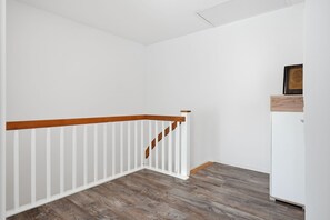 Ein Blick in einen Raum mit einer Holztreppe, einer weißen Wand und einem weißen Schrank.