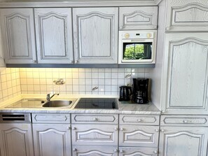 Eine Küche mit weißen Schränken, einer doppelten Spüle, einer Mikrowelle und einer Kaffeemaschine.