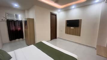 Una habitación de hotel con cama, armario, televisor montado en la pared y aire acondicionado.
