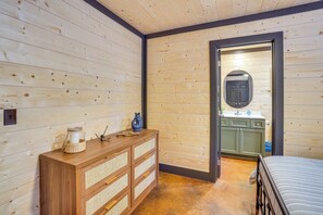 Une pièce aux murs lambrissés, avec une commode en bois, un miroir et un lit.