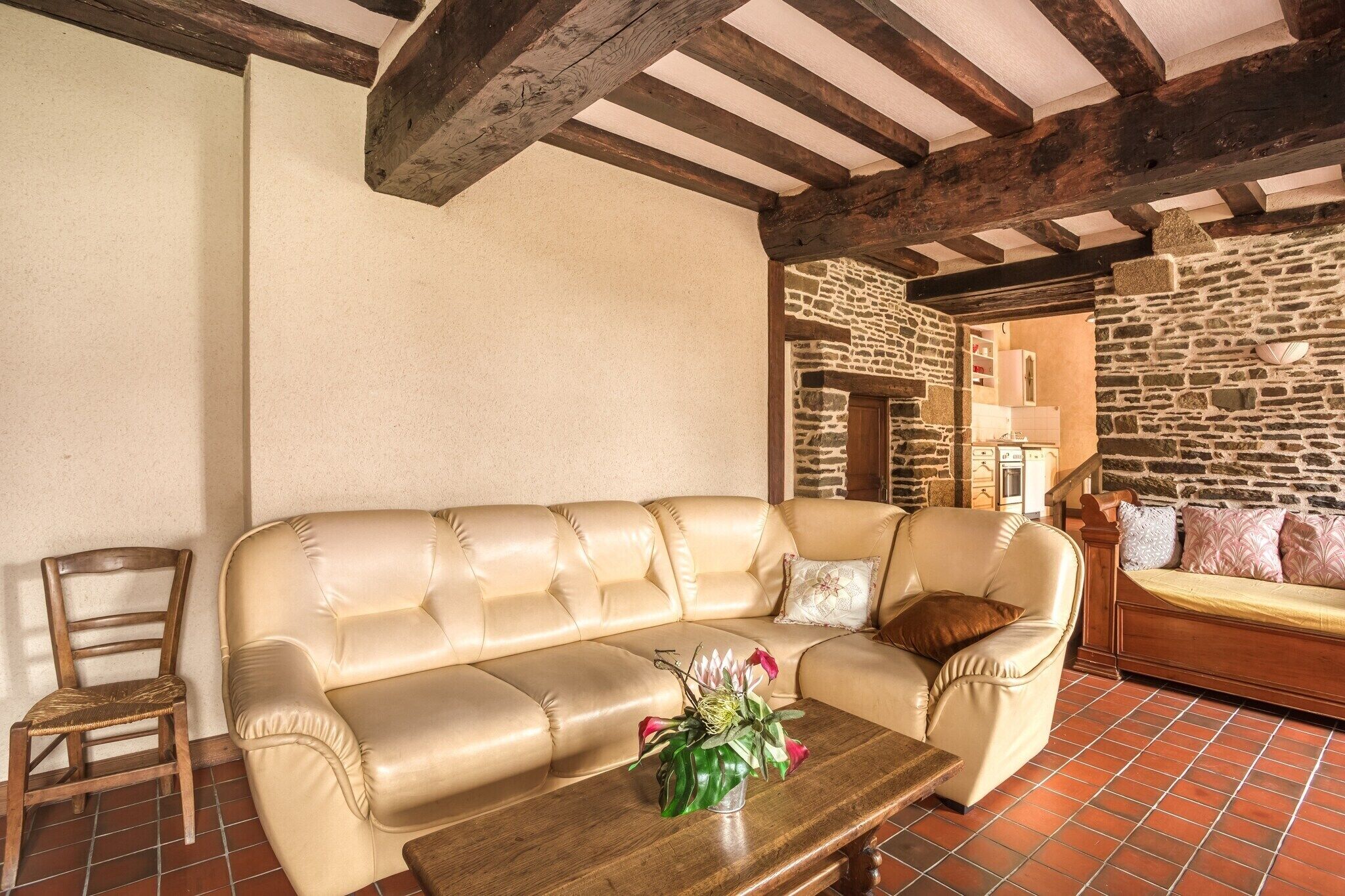 Ein Wohnzimmer mit einem beigefarbenen Sofa, einem Holztisch mit einer Vase und einer Steinwand.