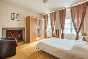 Une chambre à coucher avec un lit, une armoire, une cheminée et une fenêtre avec des rideaux.