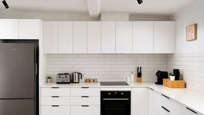Eine moderne Küche mit weißen Schränken, einem Edelstahl-Kühlschrank, einem Geschirrspüler und einem eingebauten Backofen.