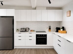 Eine moderne Küche mit weißen Schränken, einem Edelstahl-Kühlschrank, einem Geschirrspüler und einem eingebauten Backofen.