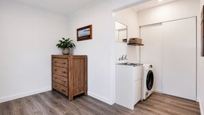Ein Waschraum mit einem Holzkasten, einer Waschmaschine, einem Waschbecken und einem Spiegel.