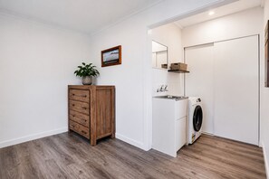 Ein Waschraum mit einem Holzkasten, einer Waschmaschine, einem Waschbecken und einem Spiegel.