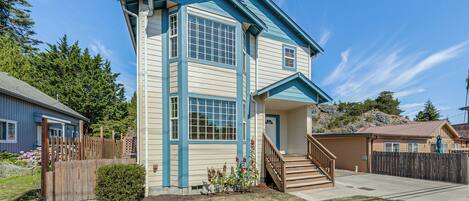 A two-story house with a front porch, a staircase, and a fenced yard.