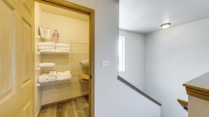 Een hotelkamer met een houten deur, een inbouwkast met planken en een trap.