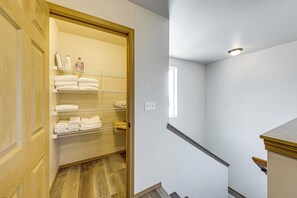 A hotel room with a wooden door, a closet with shelves, and a staircase.
