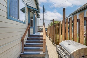 A wooden staircase leading to a house with a barbecue grill outside.