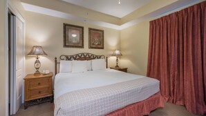 Habitación de hotel con una cama grande, dos lámparas de noche, una mesita de noche de madera, un teléfono y dos cuadros en la pared.
