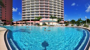 A large swimming pool with clear blue water, surrounded by a hotel building with multiple balconies. - Disney dreams Penthouse water view Mall restaurant (Orlando)