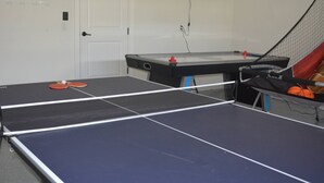 Ein Tischtennis-Tisch mit Netz in einem Raum mit Tür und weiteren Tischtennisplätzen.