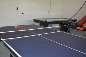 Ein Tischtennis-Tisch mit Netz in einem Raum mit Tür und weiteren Tischtennisplätzen.