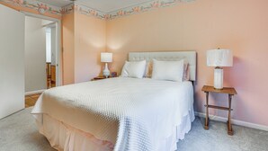 Un dormitorio con cama, dos mesitas de noche y una puerta que da a otra habitación.