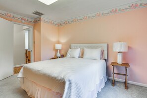 Ein Schlafzimmer mit einem Bett, zwei Nachttischen und einer Tür zu einem anderen Raum.