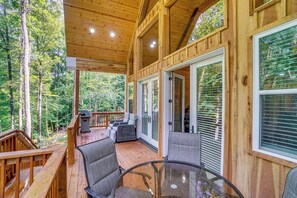 A wooden deck with outdoor furniture, a glass table, and a view of the forest. - Cabin Retreat w/ Hot Tub Near Downtown Helen! (Helen)