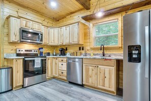 A modern kitchen with wooden cabinetry, stainless steel appliances, and a built-in water dispenser. - Cabin Retreat w/ Hot Tub Near Downtown Helen! (Helen)