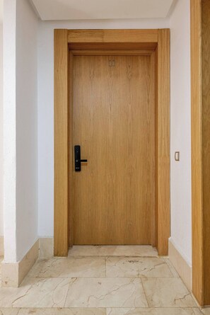 Uma porta de madeira com o número '11' e uma fechadura moderna, que dá para um chão de azulejos.