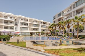 Um hotel com piscina, várias varandas e palmeiras.