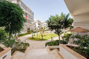 A hotel entrance with a staircase leading to a courtyard with greenery and a pool. - Beautiful apartment in Mansbay Beach next to the beach (Mansouria)