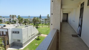 A balcony with a view of a pool, a lawn, and buildings in the background. - 1 bedroom apartment at 50 meters from the beach (Roquetas de Mar)