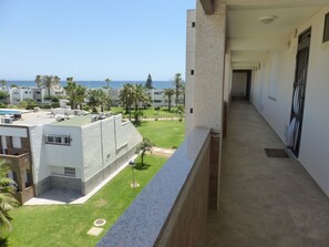 A balcony with a view of a pool, a lawn, and buildings in the background. - 1 bedroom apartment at 50 meters from the beach (Roquetas de Mar)