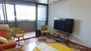 A room with a television, two yellow chairs, a sofa with orange cushions, and a checkered floor. - 1 bedroom apartment at 50 meters from the beach (Roquetas de Mar)