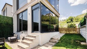Una casa moderna con amplios ventanales, una escalera de piedra y un jardín bien cuidado.