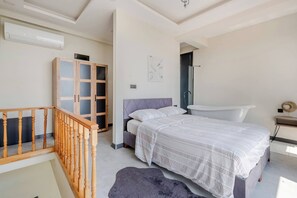 Ein Schlafzimmer mit Bett, Kleiderschrank und einem Badezimmer mit Badewanne sowie einer Treppe.