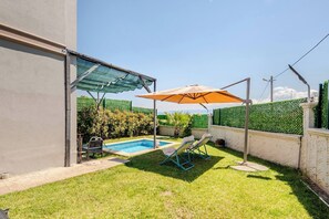 A backyard with a swimming pool, two lounge chairs, a covered patio, and a green fence. - 1 Deluxe Villa Isıtmalı Havuz, Ateş Çukuru (Dilovası)