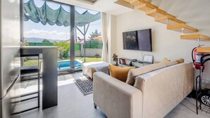 Una sala de estar moderna con un sofá, un televisor de pantalla plana y una escalera.