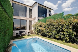 Una casa moderna con piscina, ventanas amplias y un jardín bien cuidado.