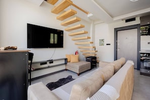 A modern living room with a wooden staircase, a flat-screen TV, a sofa, and a kitchen area. - 3 Superior Villa Heated pool and Sea View (Dilovası)