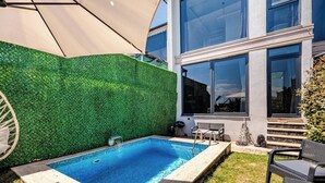 A swimming pool with a green hedge wall, outdoor furniture, and a modern building with large windows. - 2 Superior Villa Isıtmalı Havuz ve Deniz Manzara (Dilovası)
