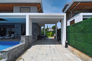Ein modernes Haus mit Pool, Sitzgelegenheiten im Freien und einer überdachten Terrasse.