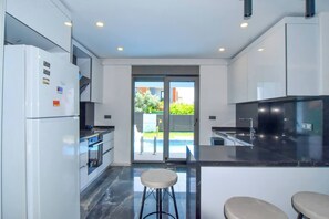 Una cocina moderna con armarios blancos, encimera negra y puerta de cristal que da a un patio.