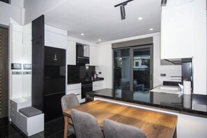 Eine moderne Küche mit einem schwarzen Kühlschrank, weißen Schränken und einem Holzespeisetisch mit Stühlen.