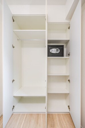 Ein begehbarer Kleiderschrank mit mehreren Einlegeböden und einem fest eingebauten Safe.